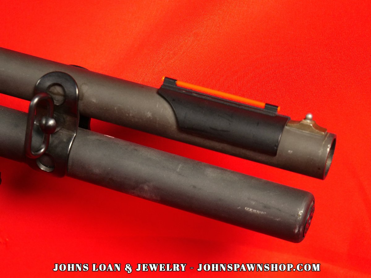 Close-up detail of the Remington 870 Magnum police shotgun barrel, featuring fiber optic front sight and matte parkerized finish, firearm available at John's Loan & Jewelry.