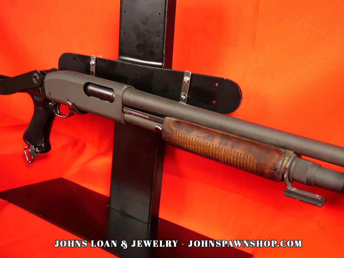 Angled view of the Remington 870 Magnum firearm, highlighting the wood forend, matte receiver, and folding stock, available for law enforcement at John's Loan & Jewelry.