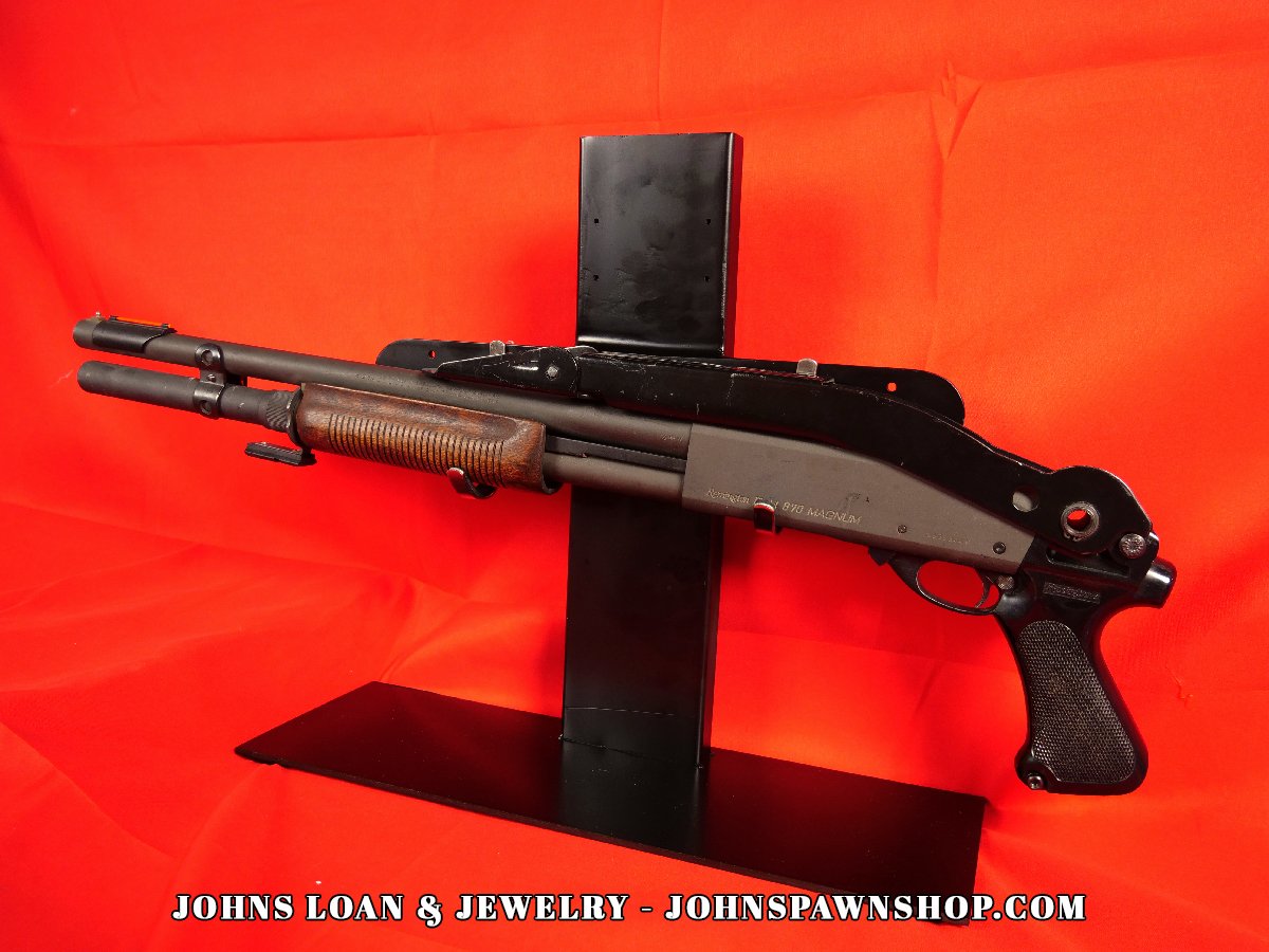 Remington 870 Magnum firearm displayed by John's Loan & Jewelry, showcasing the folding stock, wood forend, and law enforcement-only designation.