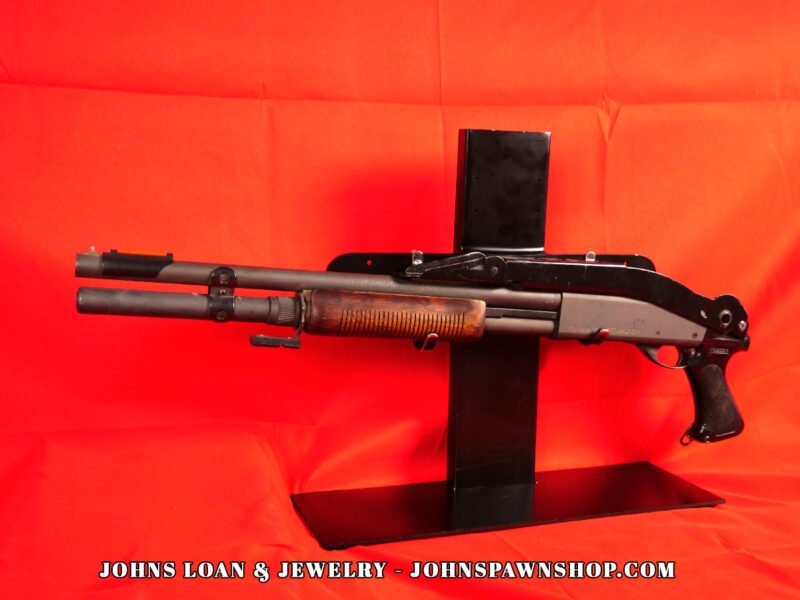 Remington 870 Magnum Police shotgun with a folding stock and ribbed wood forend, showcased by John's Loan & Jewelry, designed for law enforcement use.