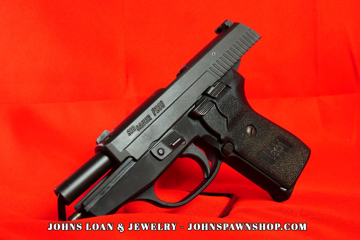 Angled view of a Sig Sauer P239 9mm semi-auto pistol on a stand, showcasing the slide and textured grip, available at John's Loan & Jewelry, your trusted pawn shop.