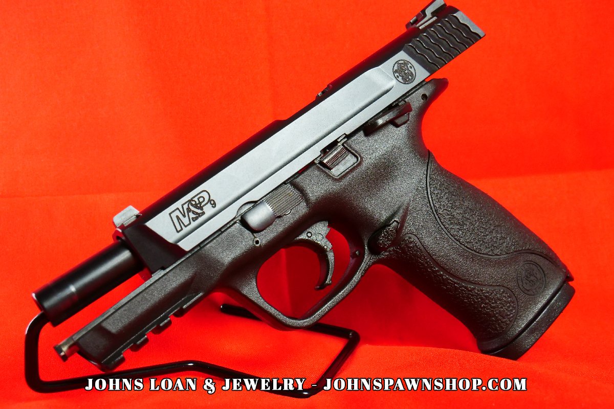 Angled view of the Smith & Wesson Military & Police 9mm semi-auto pistol, highlighting the stainless steel slide and textured grip, now at John's Loan & Jewelry.
