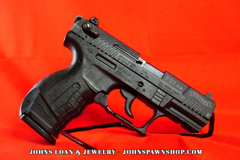 Semi-automatic Walther P22 pistol in .22LR, featuring a polymer frame and black finish, resting on a display stand, sold by John's Loan & Jewelry; great for tactical rimfire training and target practice.