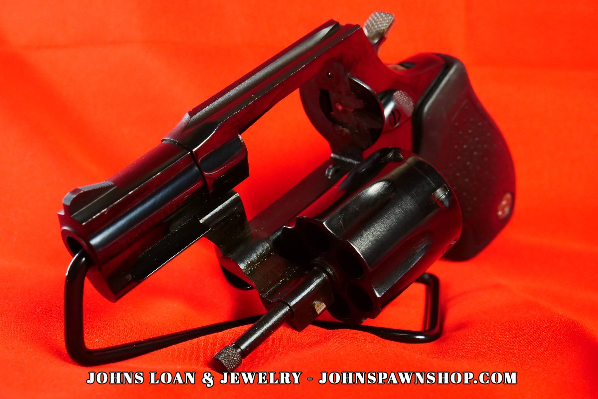 Tilted perspective of a Taurus Model 85 five shot revolver, in .38 Special, cylinder released on a stand, from John's Loan & Jewelry pawn shop.