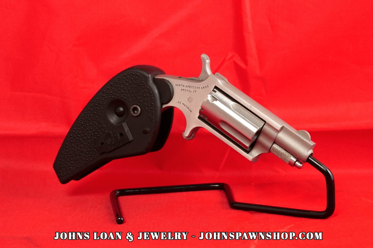 North American Arms .22 Magnum mini-revolver from John's Loan & Jewelry, showcasing its stainless steel frame, textured black holster grip, and single-action mechanism, presented on a black display stand.